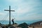 Sauofen - A woman with hiking backpack standing under a wooden cross on top of Sauofen in Austrian Alps. A vast, golden pasture