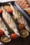 Saury grilled with vegetables on the grill pan closeup. Vertical