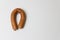 Sausage in the form of horseshoe is hanging on nail on the wall.