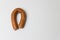 Sausage in the form of horseshoe is hanging on nail on the wall.