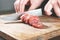 Sausage, knife, hands of woman, thick pieces, wooden plank, knife in female hands, woman cuts the sausage