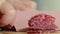 Sausage slicing, Close view woman hand's cutting sausage with sharp knife. Hand slicing salami sausage on wooden