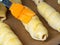 Sausages in the dough are prepared for baking. Brush the egg yolk. Close up.