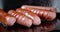 Sausages fried in a pan in oil with air bubbles.