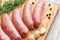Sausages for frying, garlic and dill on a bamboo cutting board
