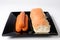 Sausages and hot dog bread on black plate on a white background