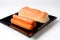 Sausages and hot dog bread on black plate on a white background