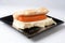 Sausages and hot dog bread on black plate on a white background