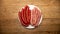 Sausages and merguez arranged in a white plate, on a woody background