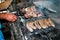 Sausages on metal grill and kebabs on skewer fried over fire, selective focus