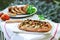 Sausages and vegetarian pies with vegetables and herbs on a wooden table in the garden. Rustic style