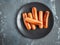 Sausages warmed up on clay on a dark ceramic plate on a gray background