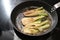 Sauteed fennel vegetable in brown butter in a cooking pan on a black stove, homemade vegetarian meal, copy space