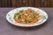 Sauteed vegetables and chicken with spices and seeds on white plate.