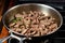 sauteing beef strips in a hot stainless-steel pan