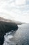 Savage seascape with impressive cliff and rocks. Heavy waves in the beach with black sand.