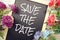 Save the Date text on blackboard decorated with flower bouquet on wooden background