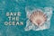 Save the ocean text on blue bakground with sea shell on top of plastic bag, respect the environment  concept