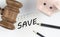SAVE text on paper with gavel and piggi bank