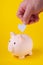 Saving money. The hand puts a heart in a piggy bank. Salary retention. Profitable investment. Health in the piggy bank.