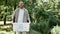 Saving the nature. Young happy man eco activist collecting plastic in the forest or park, holding recycle bin and