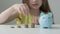 Savings, budget planning. Happy smart small 9s teen kid make donation contribution in piggy bank. Close up