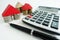 Savings and calculation for real estate investments, with house symbol from coins and wooden pieces, calculator and pen on desk