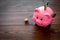 Savings. Moneybox in shape of pig with banknotes falling into it near coins on dark wooden background copy space