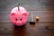 Savings. Moneybox in shape of pig with banknotes falling into it near coins and hammer on dark wooden background copy