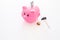 Savings. Moneybox in shape of pig with banknotes falling into it near coins and hammer on white background copy space
