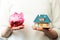 savings for new family house concept - piggy bank and house scale model in hands