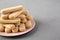 Savoiardi or ladyfingers cookies on pink plate on concrete background, side view. Copy space