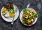 Savory breakfast - avocado, cherry tomatoes grilled  bread salad and fried egg with hummus and rye croutons on dark background,