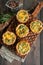 Savory mini quiches tarts on a wooden board. Flaky dough pies.