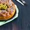 Savory pie, round monkey bread with stuffed buns oives and cheese, topped with grated cheese and black sesame bowl pitted green