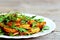 Savory roasted potatoes with arugula on a white plate. Wooden background