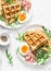 Savory waffles, boiled egg, ham and arugula on light background, top view. Appetizers, snack, brunch. Delicious healthy food conce