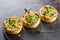 Savoury mini quiches with custard and watercress on a black round wooden board