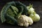 Savoy cabbage, cauliflower and kohlrabion a dark wooden table
