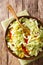 Savoy cabbage salad with corn, onions and bell pepper close-up in a bowl. Vertical top view