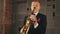 Saxophonist in dinner jacket stand on stage with golden saxophone. Jazz musician