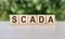 Scada word concept on cubes, gray-green background