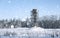 Scaffold around the water tower in field in front of forest in s