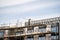 Scaffolder in PPE erecting framework of wooden planks and tall scaffolding poles high up on modern new building construction site