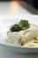 Scalding hot baked cabbage rolls with cream sauce close-up. Restaurant serving of cabbage rolls on a plate with greens