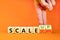 Scale up or down symbol. Concept words Scale up Scale down wooden cubes. Businessman hand. Beautiful orange table orange