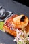 Scallops and ravioli. Seafood, pike perch fish, caviar and black dumplings in a plate on a dark table close-up. Healthy