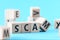SCAM word written on wooden cubes standing in a row