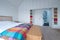 Scandi style bedroom interior with wooden bedroom furniture, white painted walls, white bedding and colourful blanket.