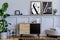 Scandinavian home interior of living room with two mock up poster frames, wooden commode, design black lamp, plants, decoration.